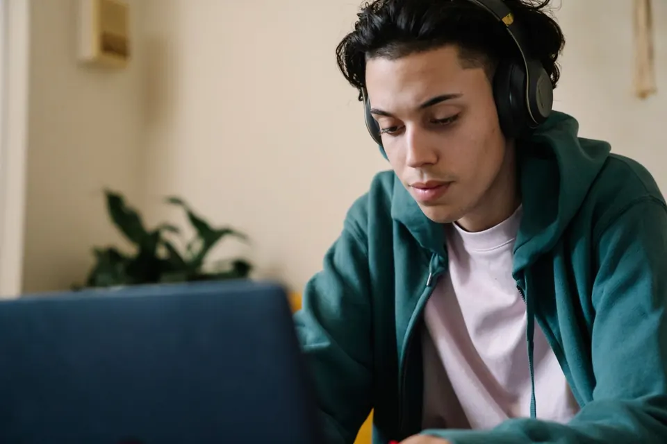 Persona adulta con auriculares estudiando frente a una notebook en casa